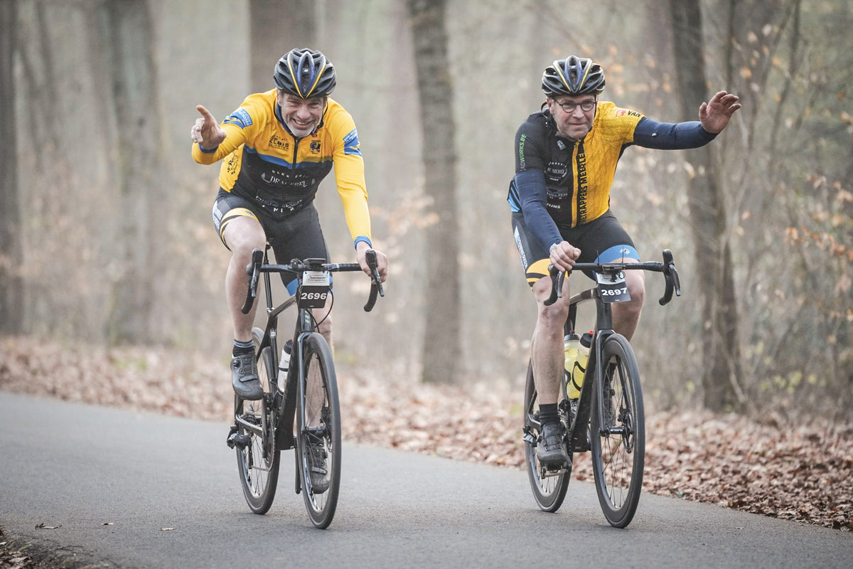 Two cyclists on a road surrounded by trees during nokere koerse cyclo