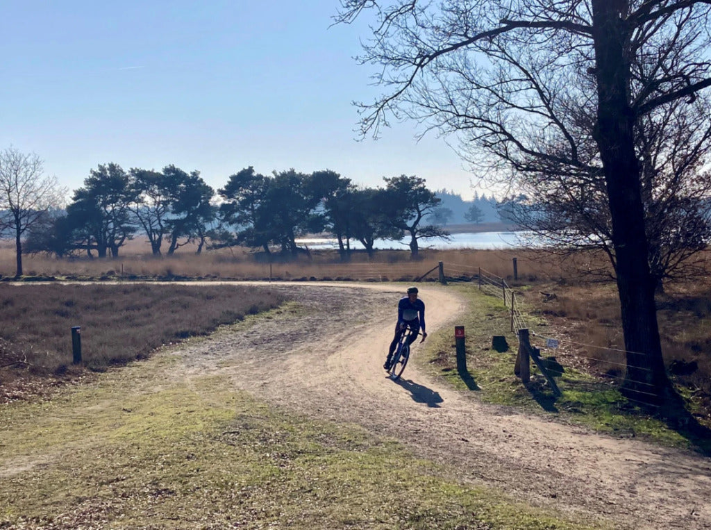 Person cycling on a dirt path in a rural landscape during plugplug groote heide